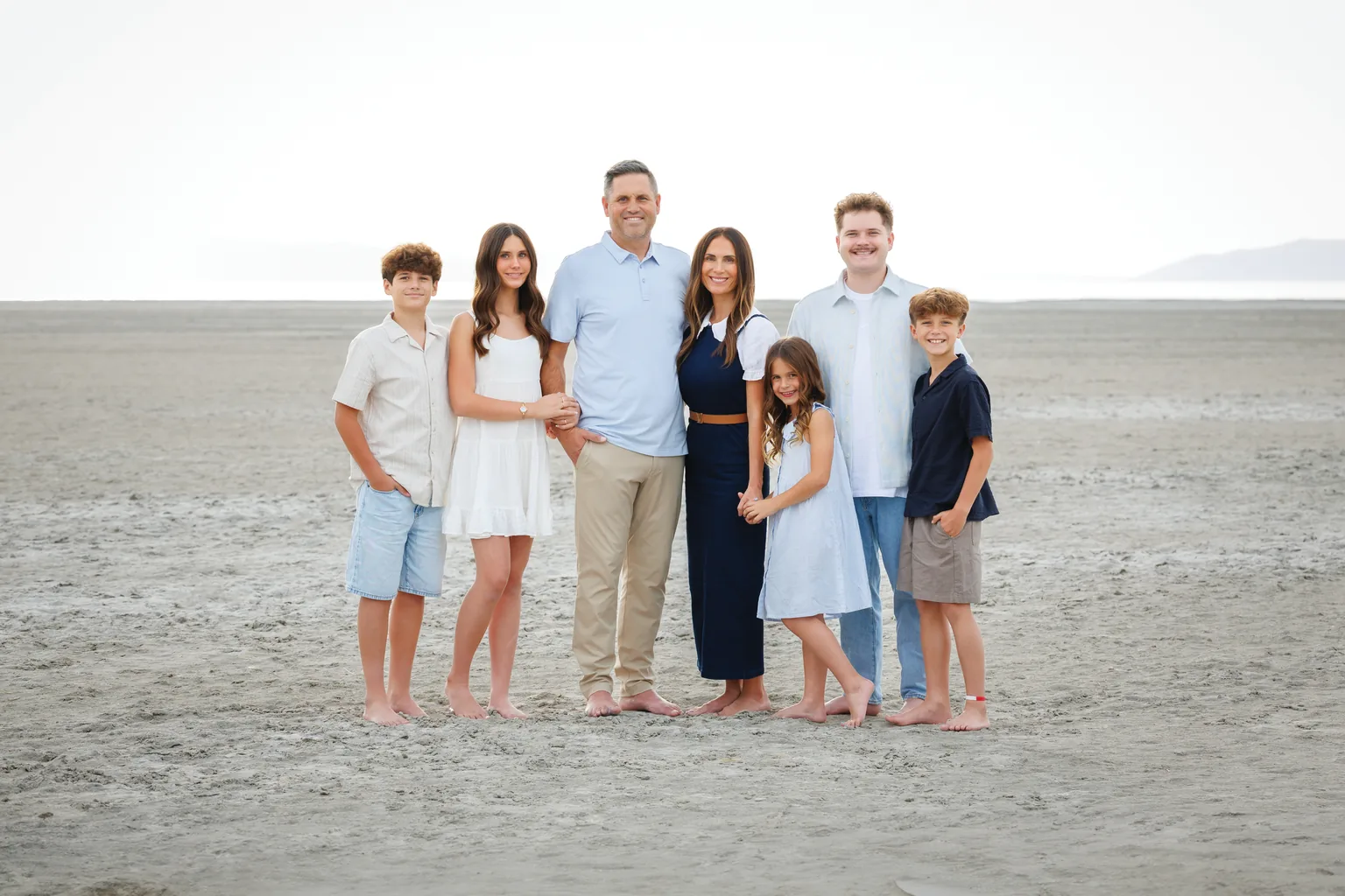 The family behind Legendary Pools and Landscapes: two parents and their five children standing together on a pale desert flat.