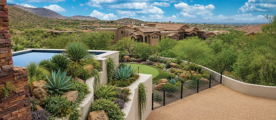 Stepped planter walls filled with agave and desert shrubs above a curved terrace, with a pool edge and a wide desert view beyond.